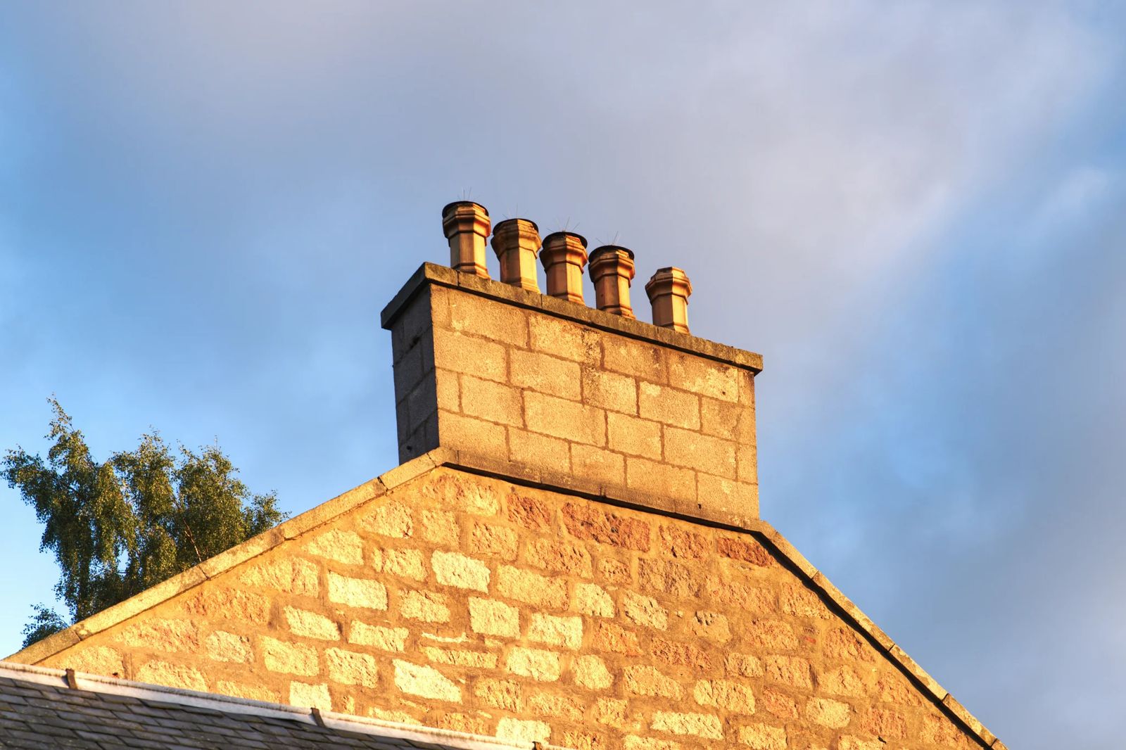 Souches de cheminée en pierre au faîte d'une toiture ancienne